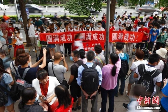 资料图：2021年6月7日，北京人大附中考点外，送考同学为考生拉横幅加油。当日，中国2021年高考正式拉开大幕，1078万名考生赶赴考场。 中新社记者 富田 摄